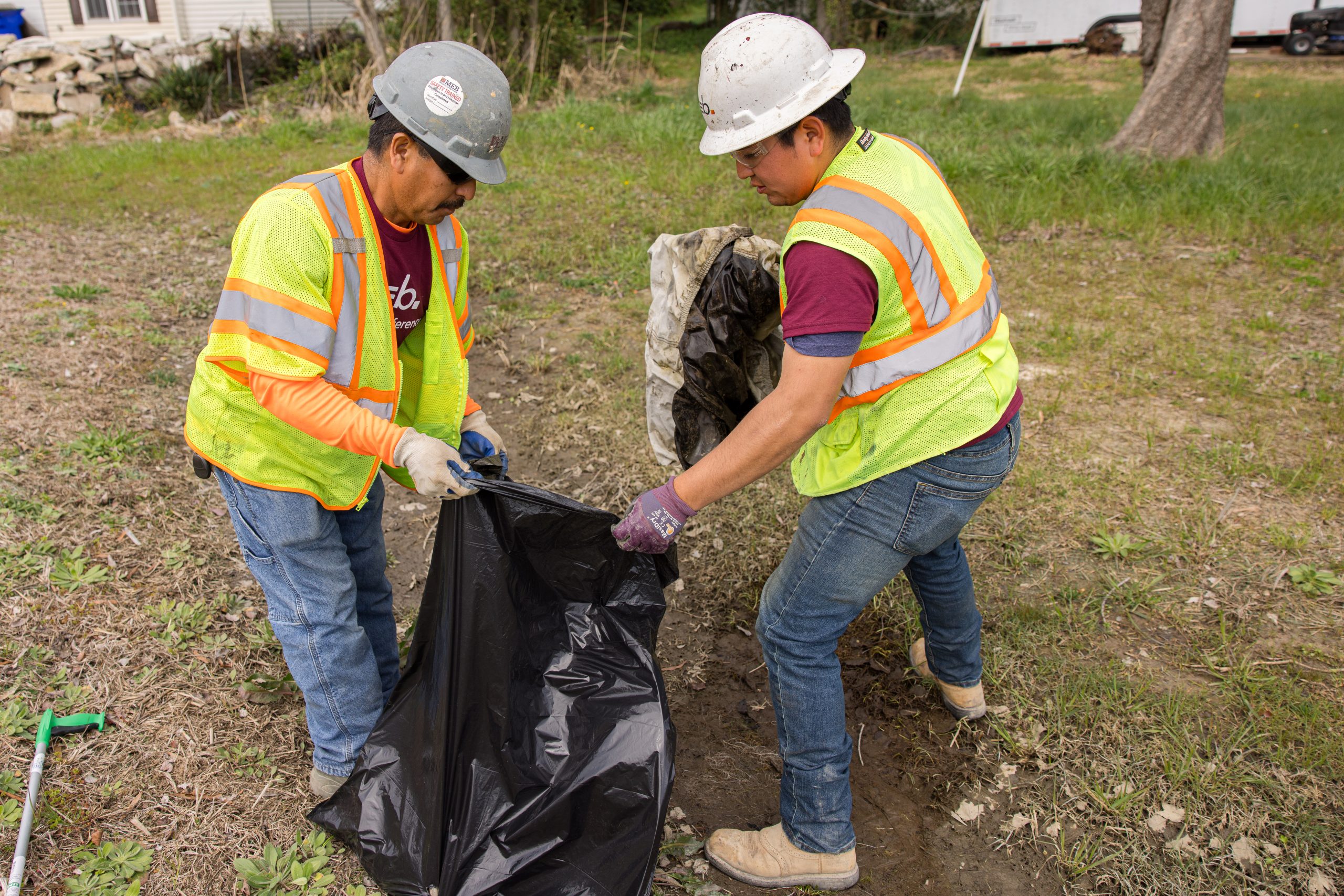 Crew members placing litter into trash bag.